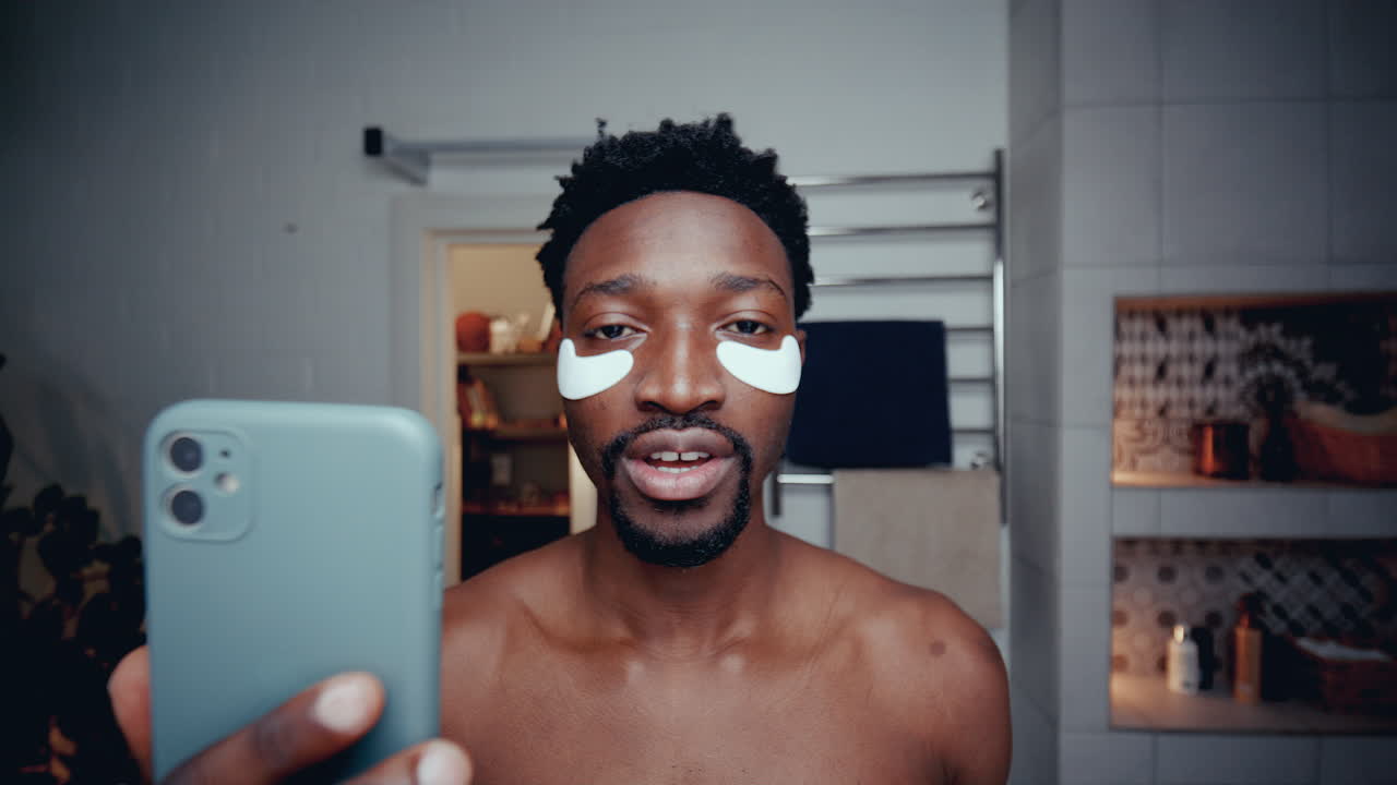 Male Blogger with Under-Eye Patches Recording Skincare Tutorial in Bathroom