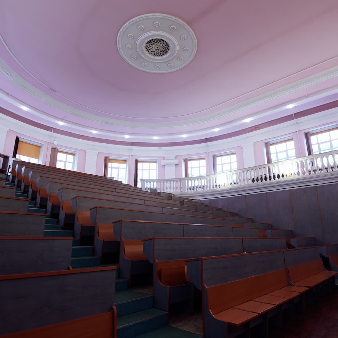Empty classroom at the university. Modern conference hall with rows of wooden tables. Interior of empty lecture room with purple ceiling