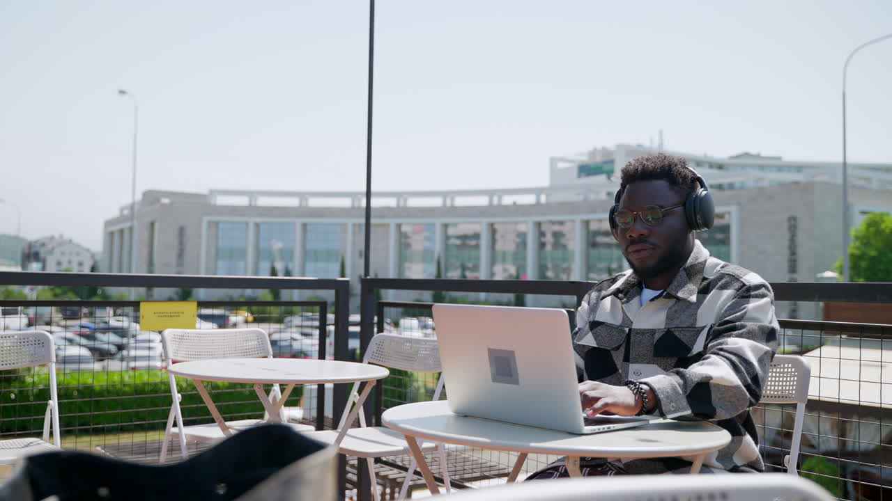 Man working on laptop in an outdoor cafe