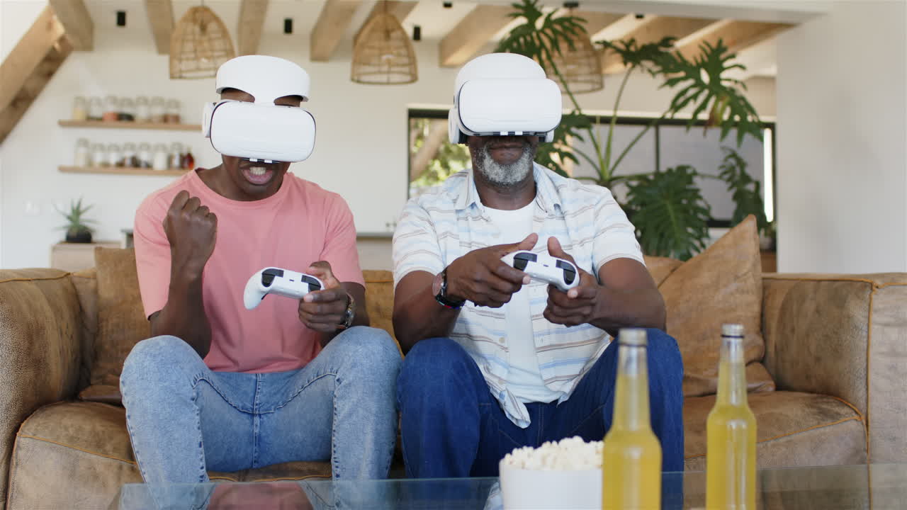 Giocando ai videogiochi con visori VR, padre e figlio adulto si godono il tempo insieme.