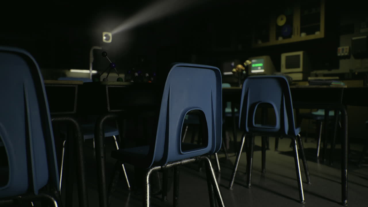 Classroom in shadows with two desks and computer setup at night