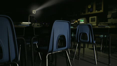 classroom in shadows with two desks and computer setup at night