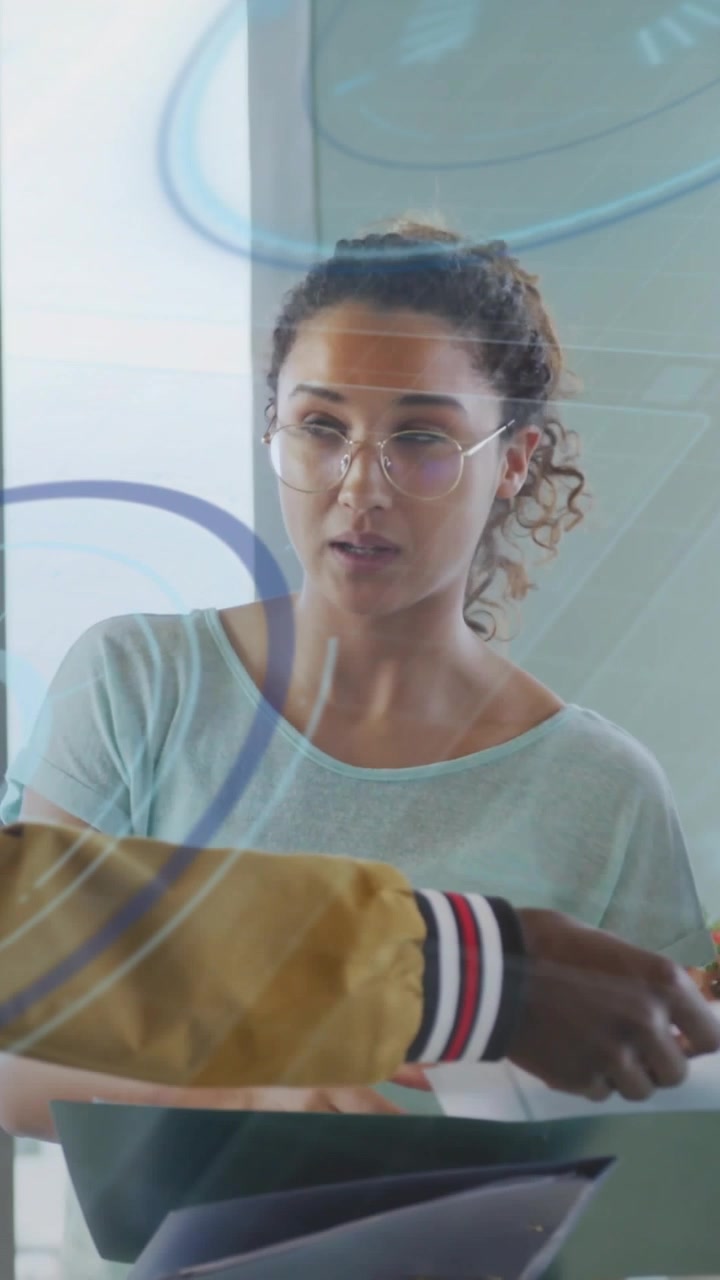 Video verticale: Donna che tiene dei faldoni, accetta un foglio, indica una vetrata e sfoglia documenti per la revisione.