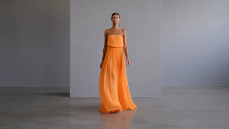 elegant woman in a strapless orange pleated gown