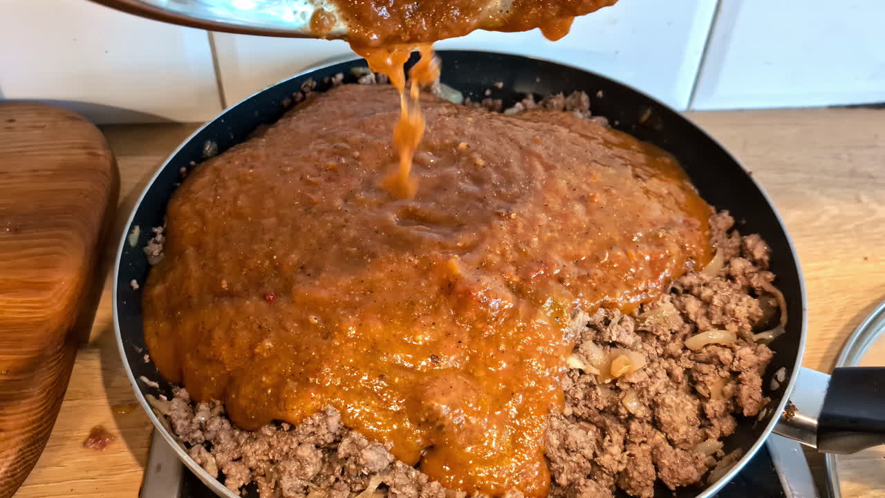Closeup view of Ground meat with gravy getting poured on.