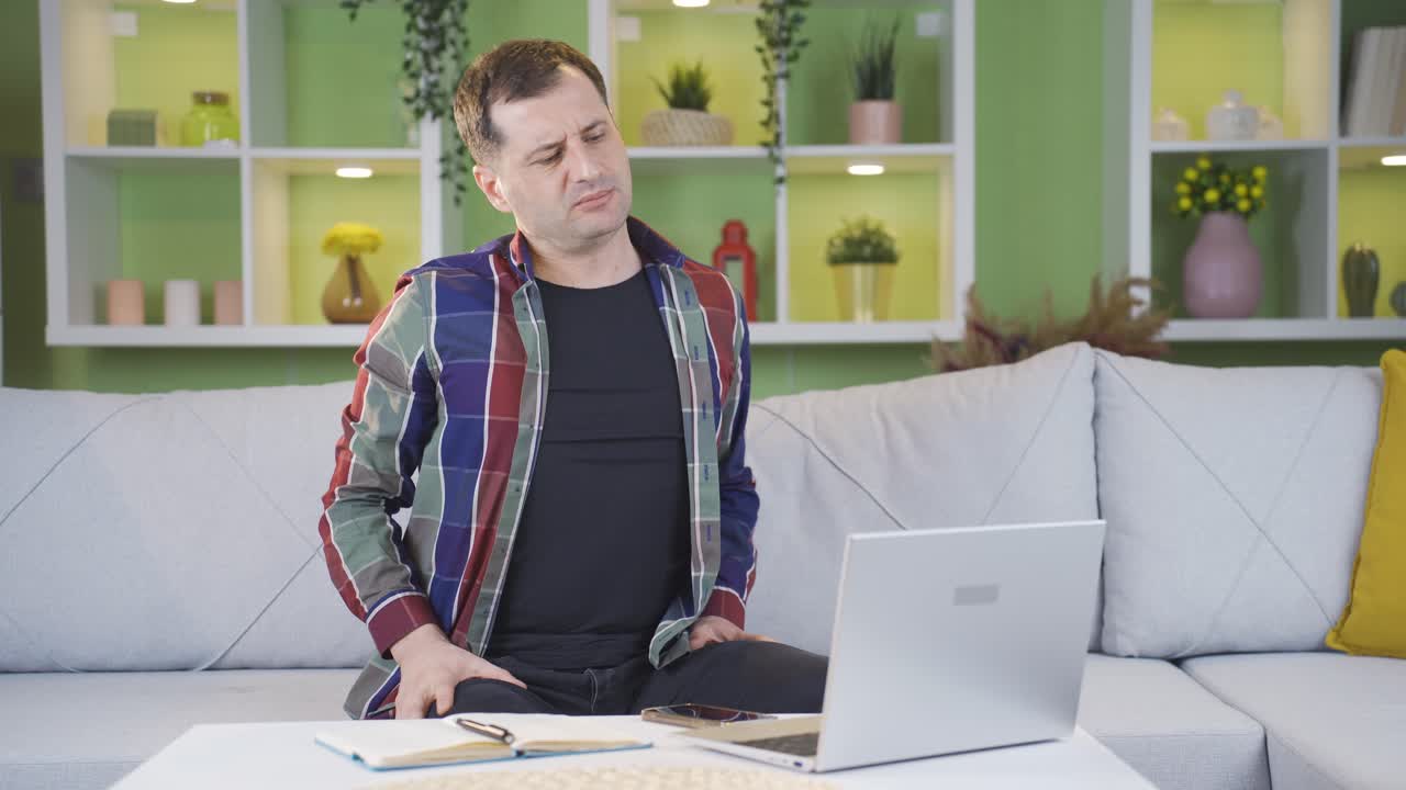 hombre con dolor de espalda por sentarse en una posición incorrecta mientras trabaja.