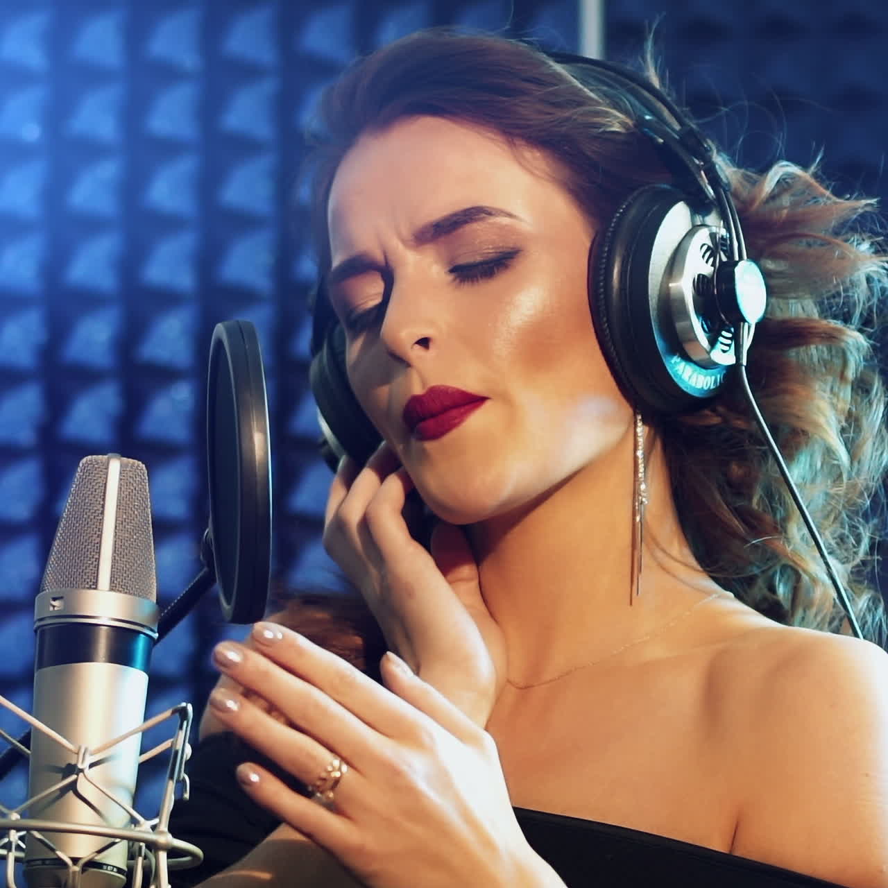 Vinnitsa, Ukraine - May 2019: Audio recording studio. Woman with headphones and studio microphone singing. Slow motion