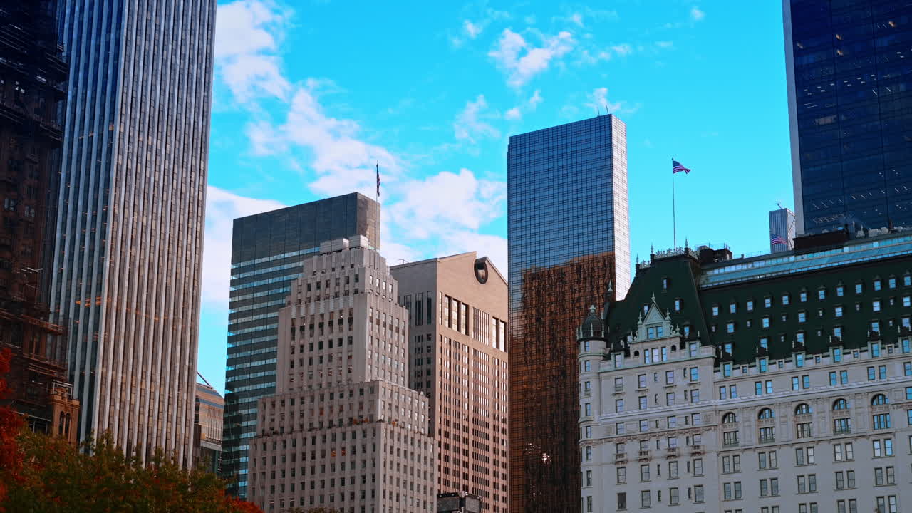 Grattacieli di Manhattan sopra Central Park, primi piani. Uno sguardo dettagliato ai grattacieli di Manhattan che si ergono sopra le cime degli alberi autunnali di Central Park sotto un cielo blu