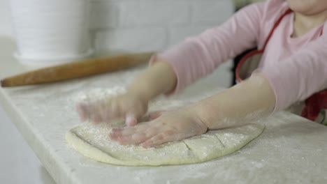 a little girl is making dough in the kitchen