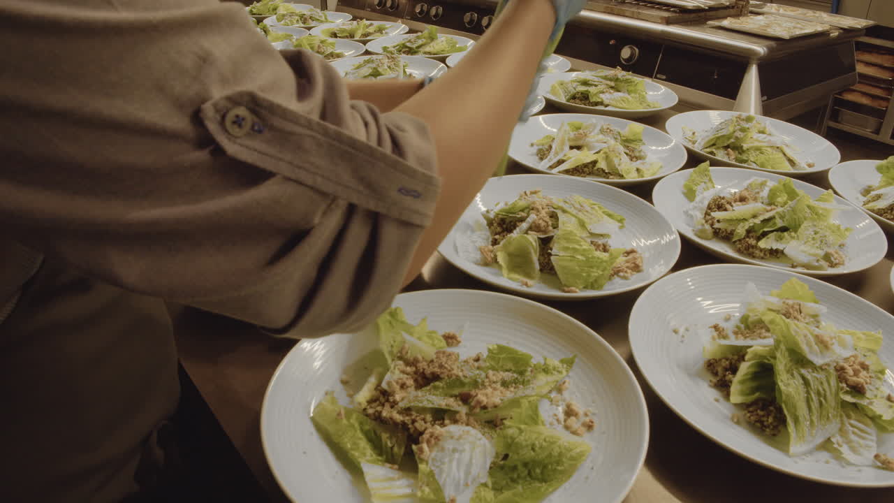 una persona que usa una manga pastelera para aplicar salsa a las ensaladas.