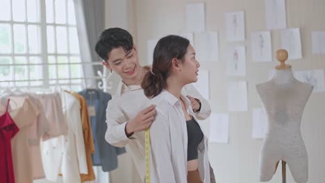 man tailor takes measures with female models. fashion designer sews a costume for the model