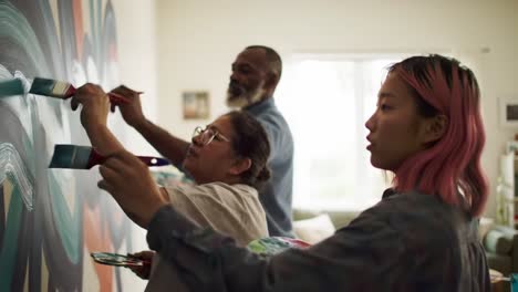 three artists engage in painting a vibrant mural on a large wall in a well-lit studio. their focus and teamwork showcase the joy of creative expression.