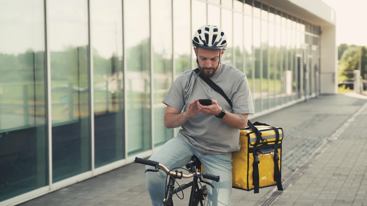 Food Delivery Guy Wearing Thermal Backpack Uses The Geolocator On His Smartphone To Navigate To The Delivery Location Riding A Bike