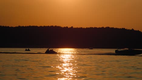 motor boat speeds down the lake at sunset