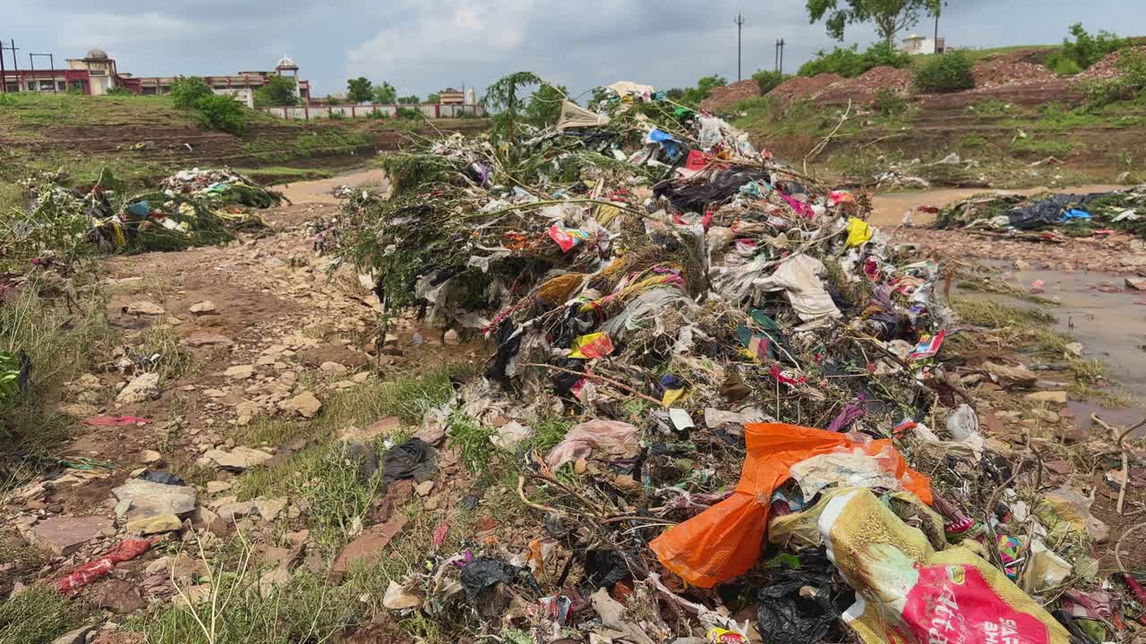 Tracking shot showing plastic, paper, and organic matter as heavy rain leading to river flooding can causing a significant buildup of garbage on plants and in surrounding areas