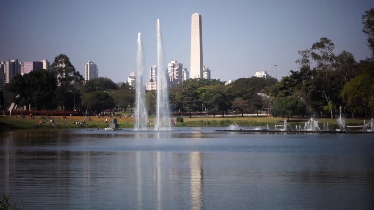 water fountains on the lake of Ibirapuera park, with cityscape and obelisk on the back. Sao Paulo, Brazil