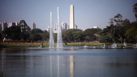 water fountains on the lake of ibirapuera park, with cityscape and obelisk on the back. sao paulo, brazil