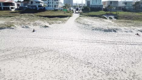 Drone-aerial-zoom-out-over-beach-and-ocean-on-summer-day