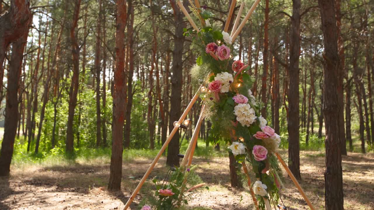 보헤미안 티피 아치 (bohemian tipi arch) 는 분홍색 장미로 장식된 나무 막대기로 만들어졌으며, 카에 불, 파스 풀, 파인 숲의 야외 결혼식 장소에서 요정의 불빛으로 감싸져 있습니다.