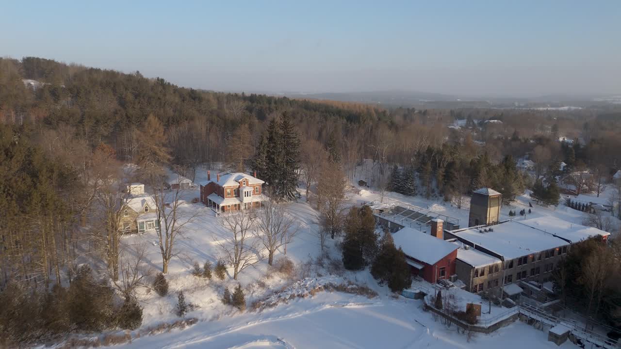 Skating Rink On A Pond At The Alton Mill At Sunrise During Winter In Ontario, Canada. Aerial Flyover.