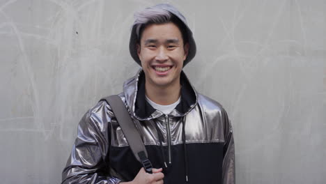 Porträt-Eines-Erfolgreichen-Jungen-Asiatischen-Studenten,-Der-Lacht-Und-Den-Entspannten-Urbanen-Lebensstil-Genießt,-Der-Eine-Stilvolle-Silberne-Jacke-Trägt-Und-Eine-Serie-Echter-Menschen-Trägt