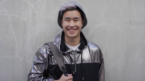 portrait successful young asian man student laughing enjoying relaxed urban lifestyle wearing stylish silver jacket real people series