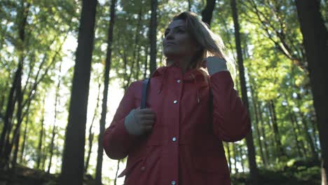 una mujer optimista camina a través de un bosque exuberante y soleado.