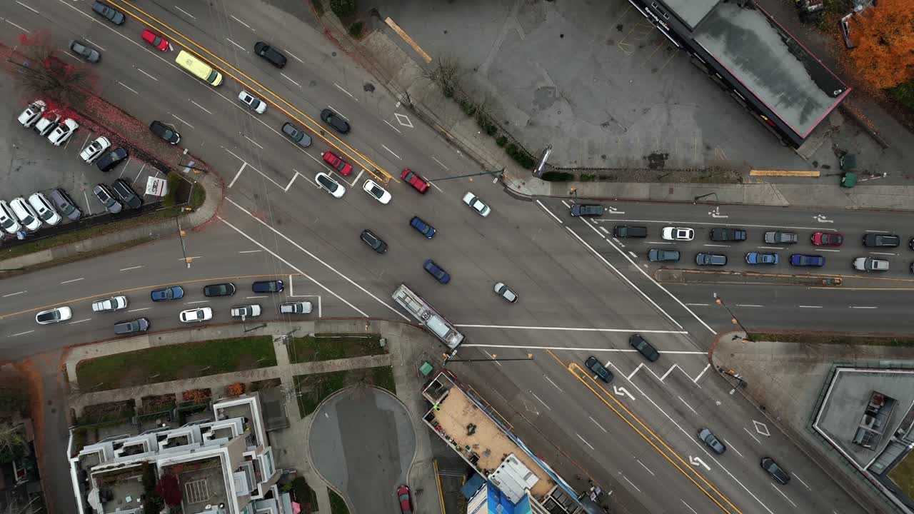 Vancouver, Canada - Multiple Lanes of Busy Traffic Move through a Large Intersection Lined with Cars and Painted Road Markings - Aerial Ascend Shot