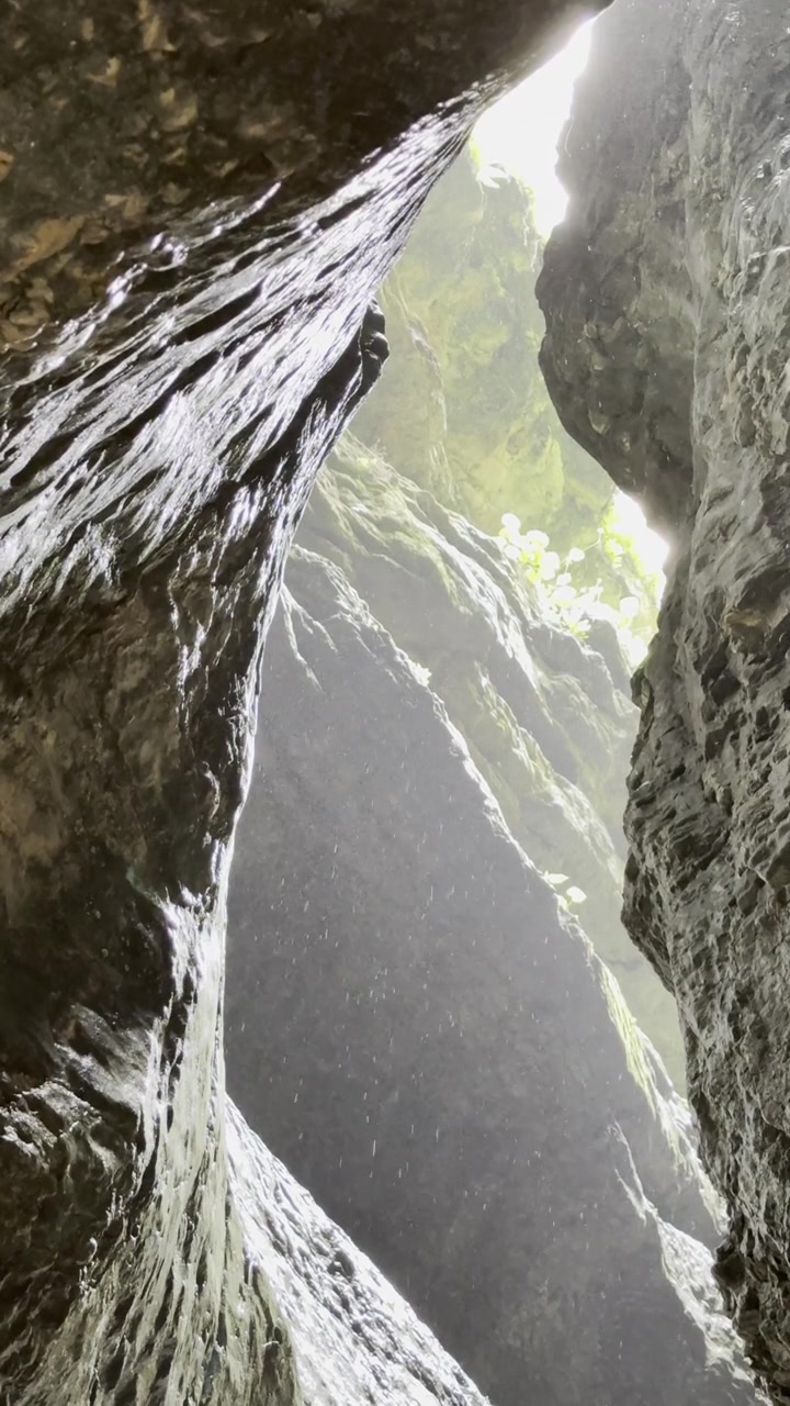 Alzando lo sguardo attraverso una stretta gola nel Distretto di Gunibsky, Repubblica del Dagestan, Russia, mentre la luce del sole filtra dall'alto e goccioline d'acqua cadono.