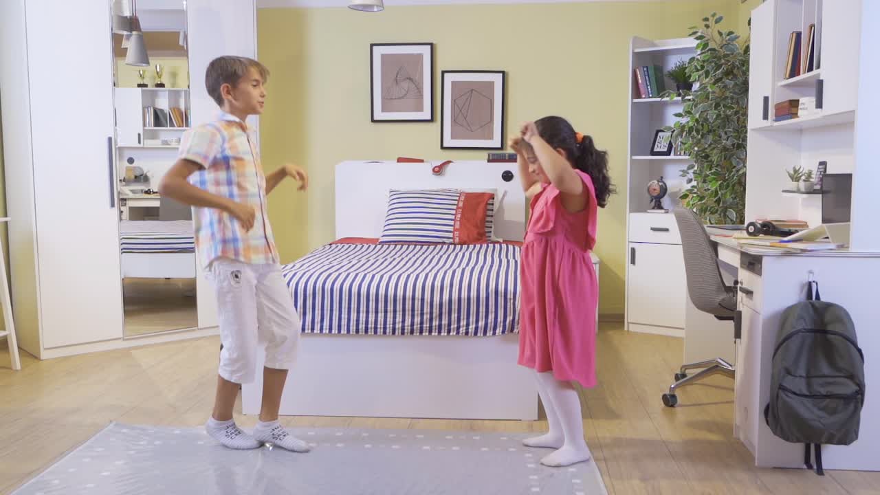 el chico y la chica están bailando en la habitación.