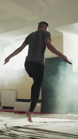 sportsman jumps on rope in combat gym. strong boxer does exercises with skip rope in martial arts club slow motion. leg muscles training techniques