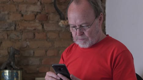 Ein-Mann-Mittleren-Alters-Mit-Grauem-Bart,-Der-Mit-Seinem-Handy-SMS-Schreibt