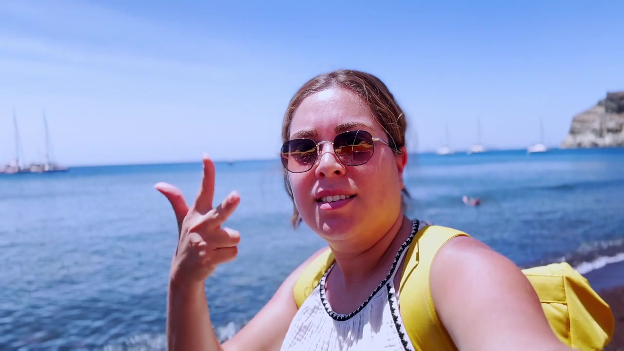 Influencer che fa vlogging sulla spiaggia rossa di Santorini, Grecia