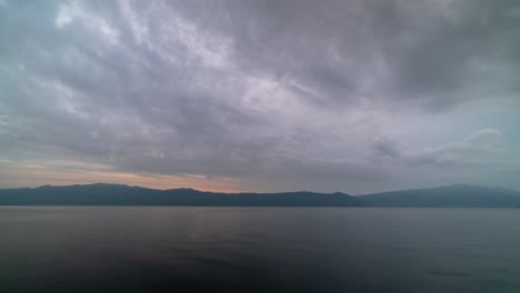 cloudy twilight sky over a calm lake and distant mountains