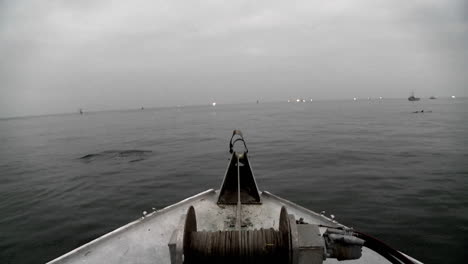 a swimmer swims across in front of a boat