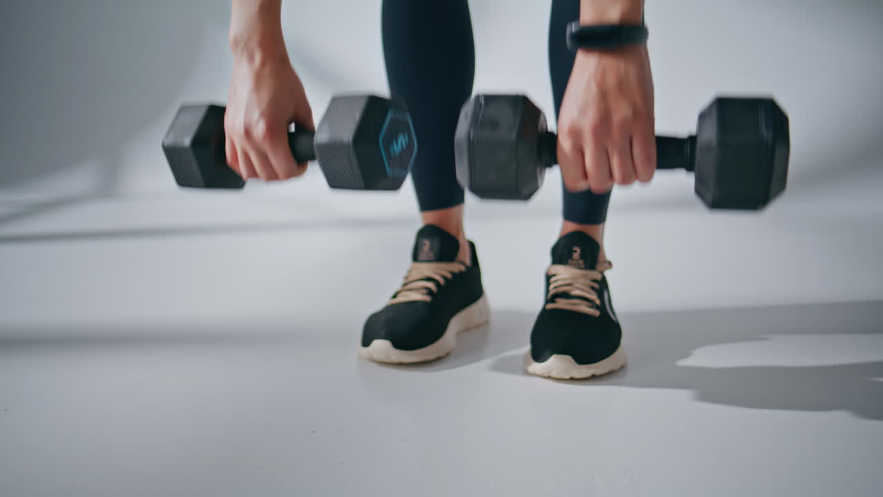 Athlete hands lifting weights in gym closeup. Fitness woman putting dumbbells