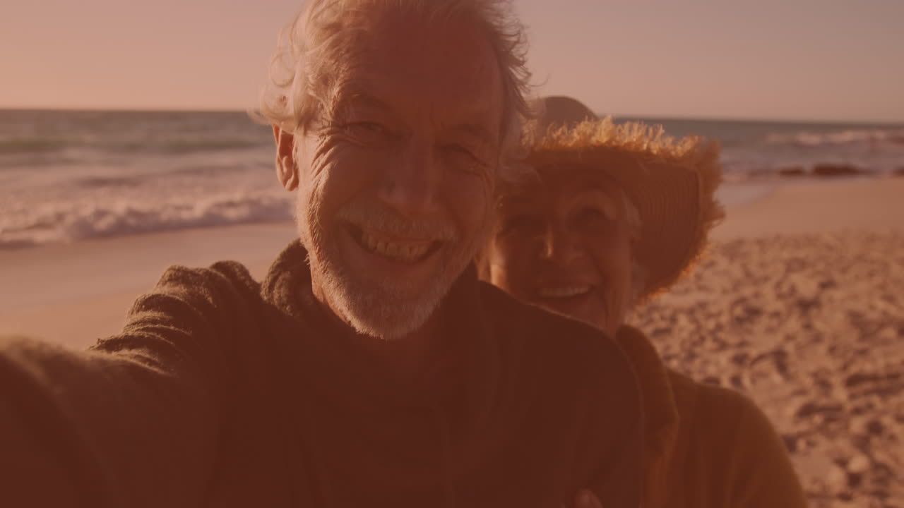 Felice coppia anziana caucasica che si scatta un selfie insieme in spiaggia