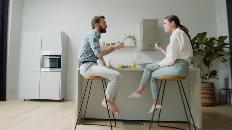Happy Couple Chatting And Having Lunch Together Sitting On Stool In A Modern Kitchen