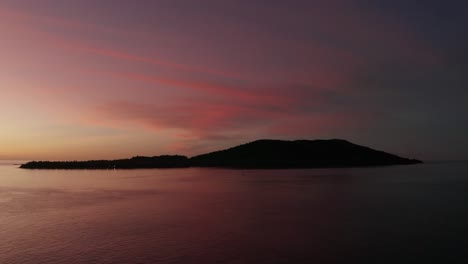 a silhouette of the mountains in the middle of a beautiful ocean in fiji at sunset - wide shot