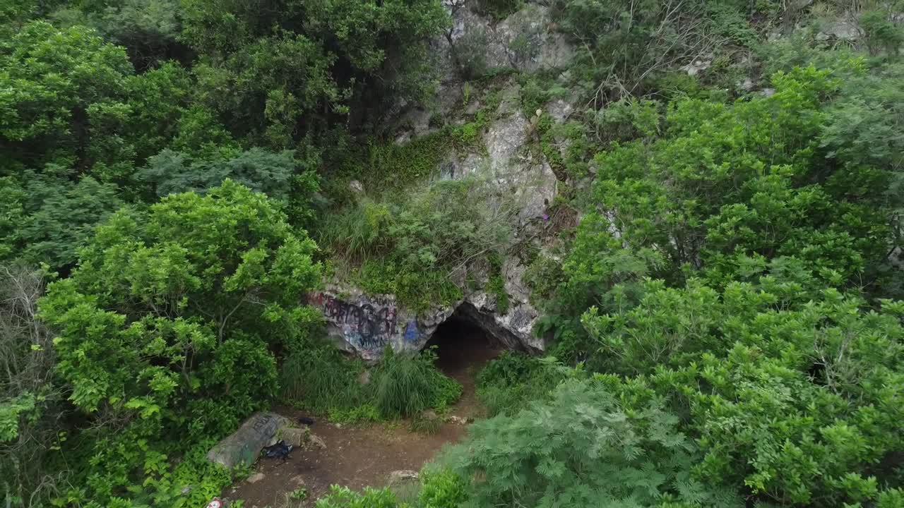 cueva solitaria con muchas pinturas en medio de la nada en un gran cerro o montaña con muchos árboles alrededor