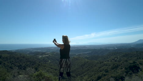 corredora tomando un descanso en las montañas y haciendo un video de la hermosa vista