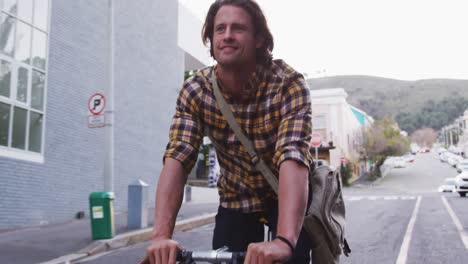 hombre caucásico sonriendo y montando su bicicleta en una calle