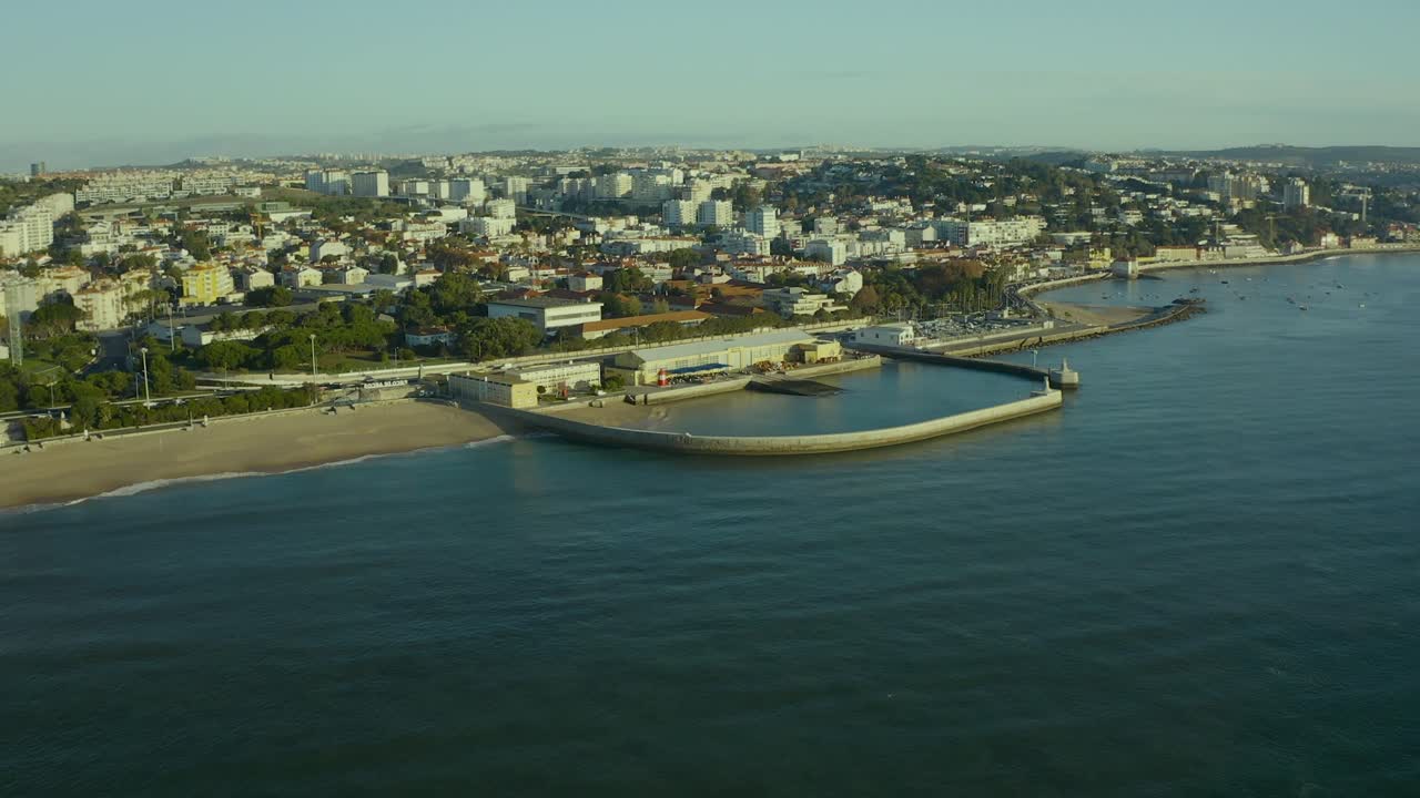 vista aérea de la ciudad de oeiras sobre el mar y la playa de paço de arcos, portugal, al atardecer.
