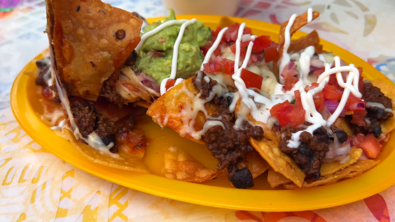 comiendo nachos mexicanos tradicionales de texas y méxico con carne de res, chile con carne, guacamole, queso derretido y crema agria, chips de tortilla totopos, comida sabrosa, tiro de 4k