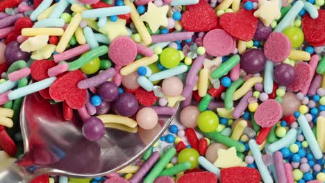 a spoon scoops vibrant, multicolored sprinkles in a macro close-up, highlighting texture and color variety