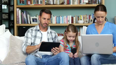 Linda-Familia-Usando-Tecnologías-Sentadas-En-El-Sofá