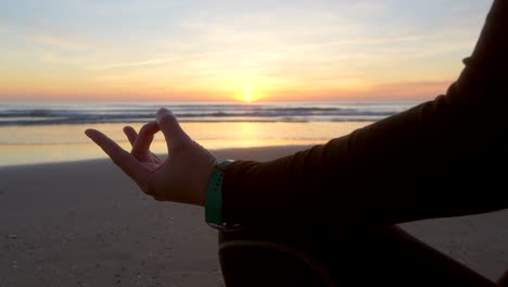 hand silhouette of a woman who is doing yoga in lotus in front of the sea