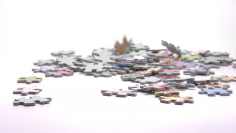 Puzzle Pieces Falling Down On White Surface - close up, slow motion