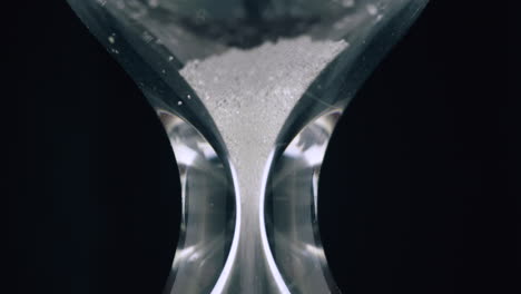 fine sand pours down inside glass clock to measure time