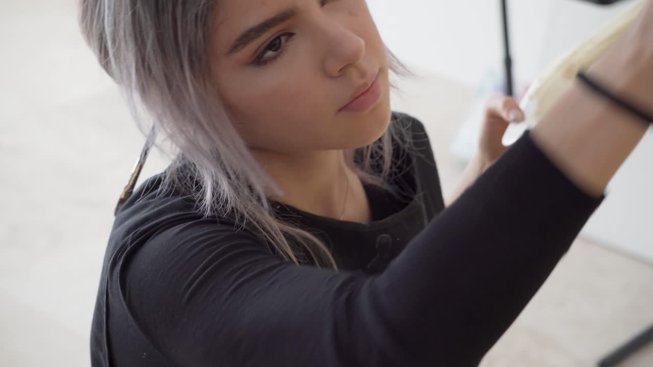 una artista con un gran pincel crea una obra de arte en un estudio de galería.